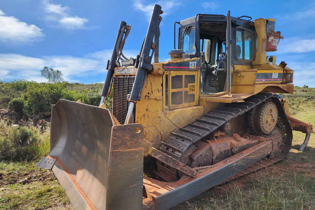 Yellow bulldozer parked in a grass field