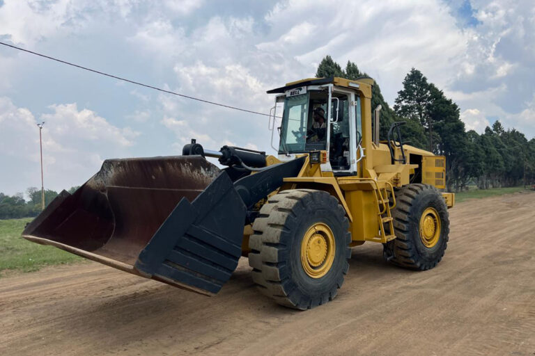 Yellow front end loader parked on a dirt road